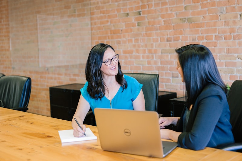 Two people talking across a table with a laptop between them